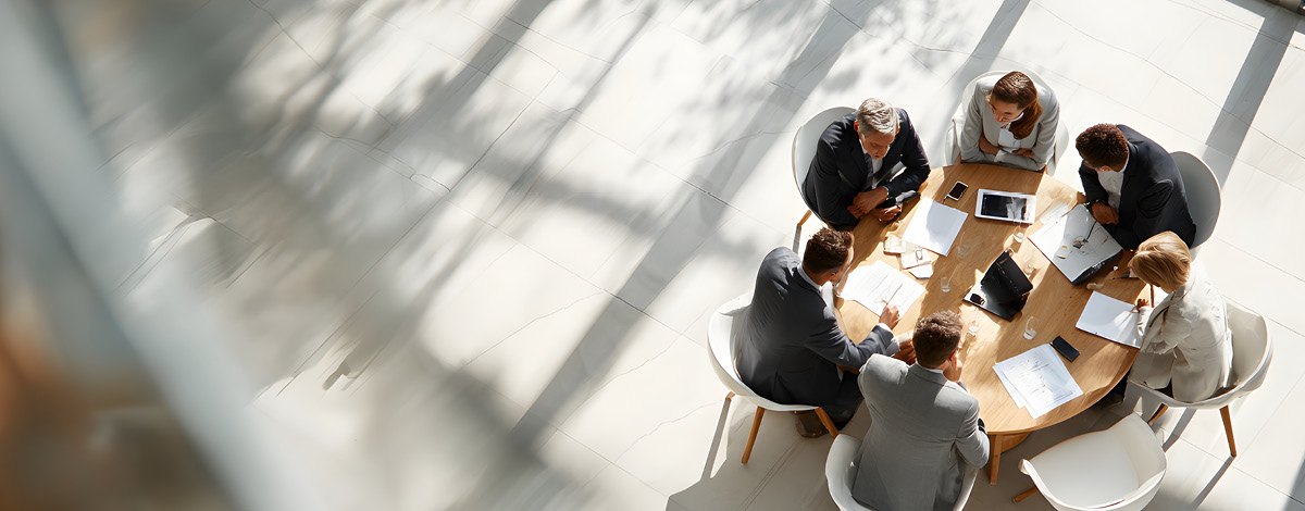 Top-down view of a meeting with 6 people sitting at a table.